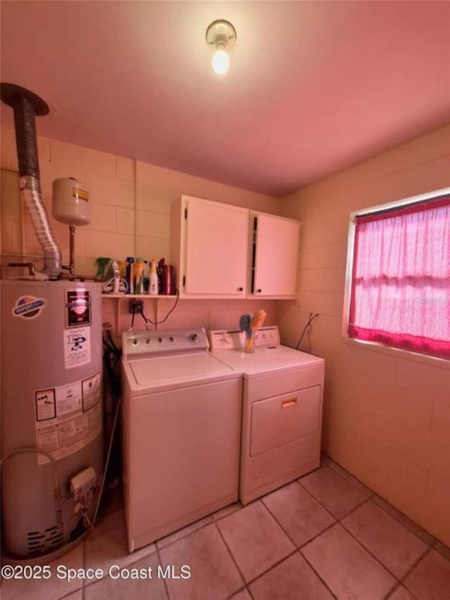 washroom with cabinets, light tile patterned floors, water heater, and washing machine and clothes dryer