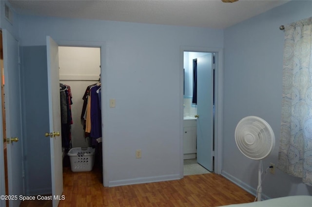 bedroom featuring a walk in closet, a closet, wood-type flooring, and ensuite bathroom