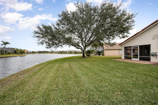 view of yard featuring a sunroom and a water view