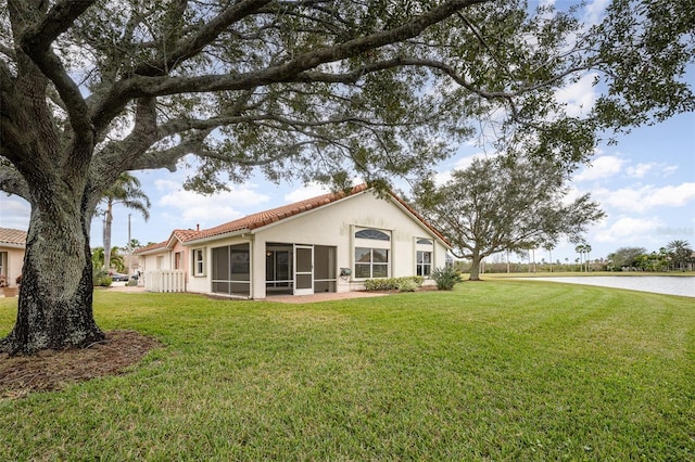 rear view of house featuring a yard and a sunroom