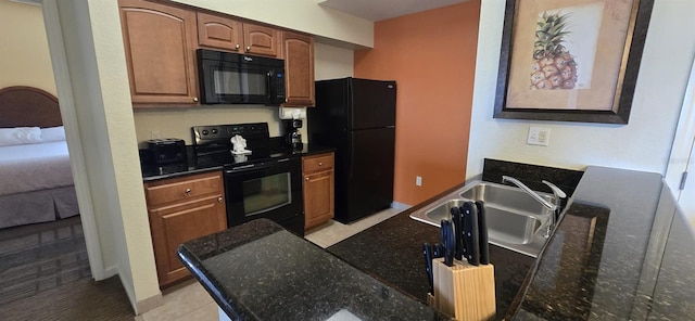 kitchen featuring light tile patterned floors, dark stone countertops, sink, and black appliances