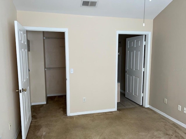 unfurnished bedroom with a spacious closet, connected bathroom, light colored carpet, and a closet