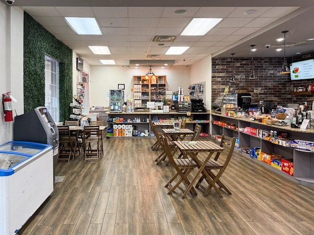 interior space with brick wall, a paneled ceiling, and hardwood / wood-style floors