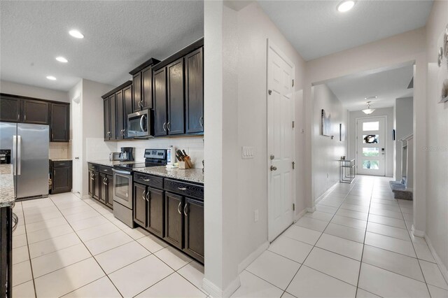 kitchen with stainless steel appliances, light stone countertops, light tile patterned floors, and backsplash