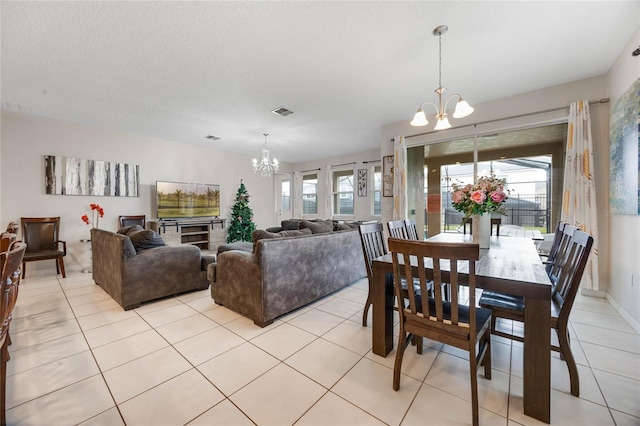 tiled dining area featuring plenty of natural light, a chandelier, and a textured ceiling