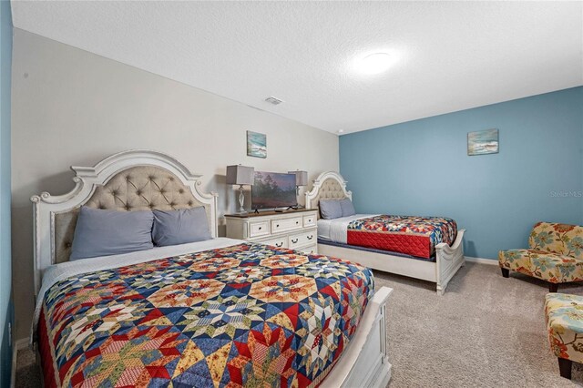 bedroom with light carpet and a textured ceiling