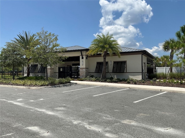 view of building exterior with uncovered parking and fence
