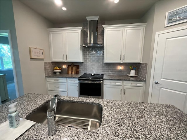 kitchen with dark stone countertops, white cabinets, wall chimney exhaust hood, and stainless steel electric stove