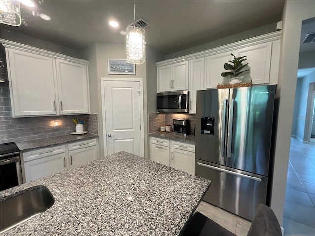 kitchen featuring light stone counters, stainless steel appliances, visible vents, white cabinetry, and backsplash