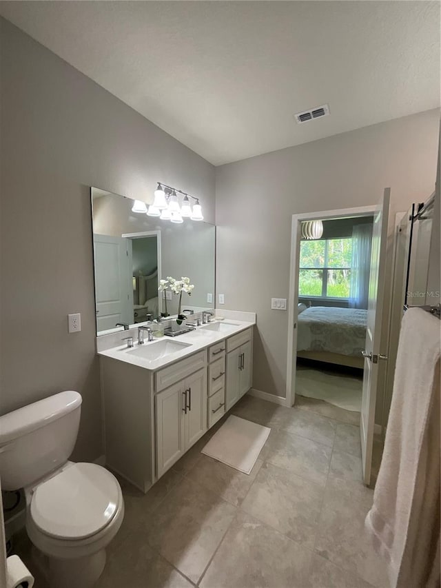ensuite bathroom featuring visible vents, connected bathroom, a sink, and double vanity
