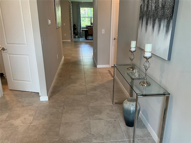 hall featuring tile patterned flooring and baseboards