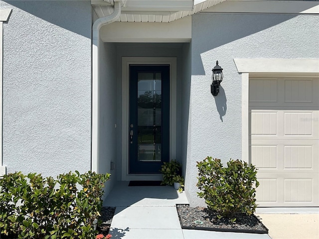 property entrance featuring a garage and stucco siding