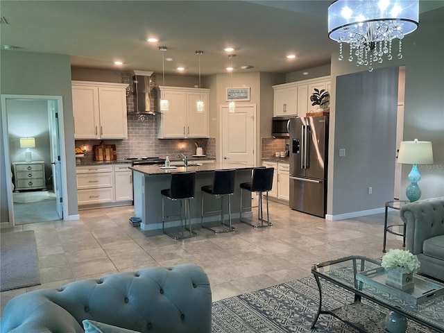 kitchen with open floor plan, wall chimney exhaust hood, appliances with stainless steel finishes, and white cabinets