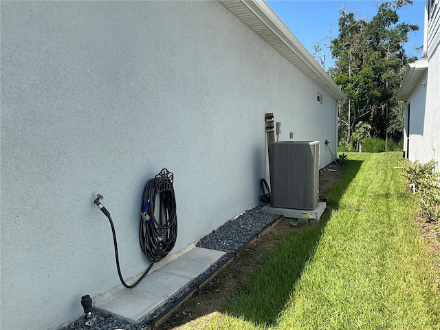 view of home's exterior featuring central AC unit, a lawn, and stucco siding