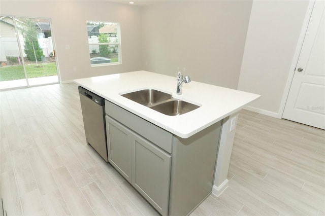 kitchen with a center island with sink, sink, stainless steel dishwasher, and gray cabinets