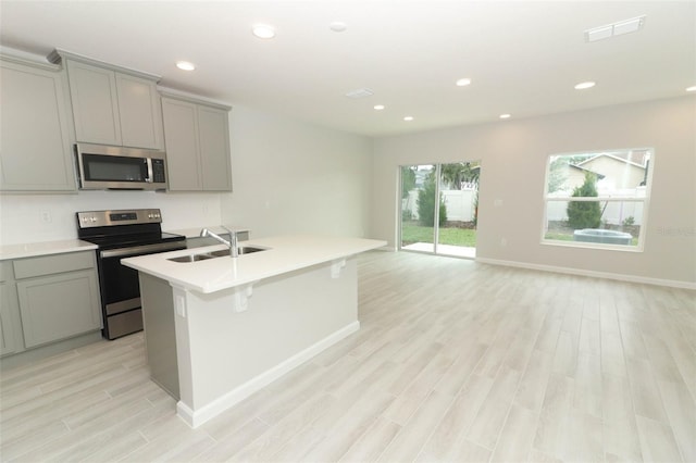 kitchen featuring gray cabinets, an island with sink, appliances with stainless steel finishes, and sink