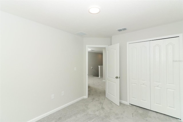 unfurnished bedroom with light carpet and a closet