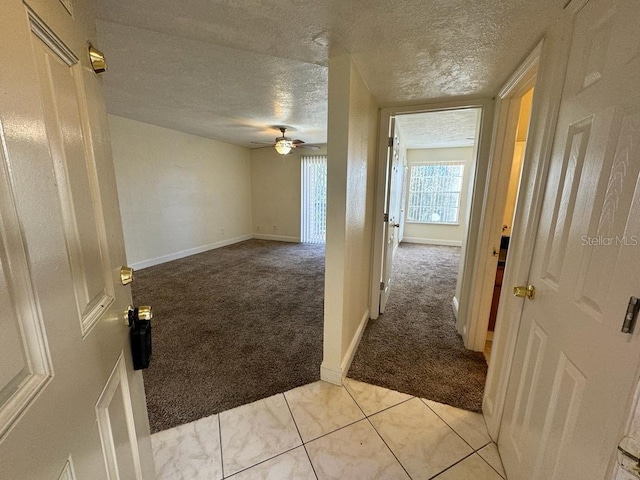 hallway with light colored carpet and a textured ceiling