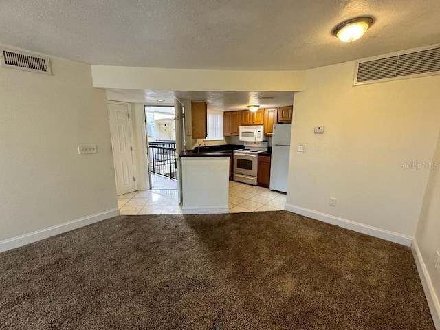 kitchen with white appliances, light carpet, and a textured ceiling