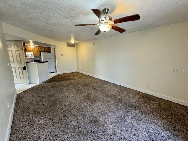 unfurnished living room featuring ceiling fan, light colored carpet, and a textured ceiling