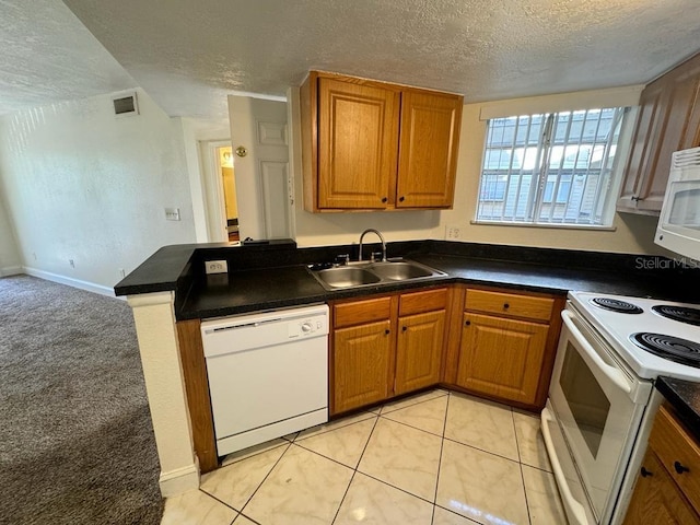 kitchen featuring white appliances, kitchen peninsula, sink, and a textured ceiling