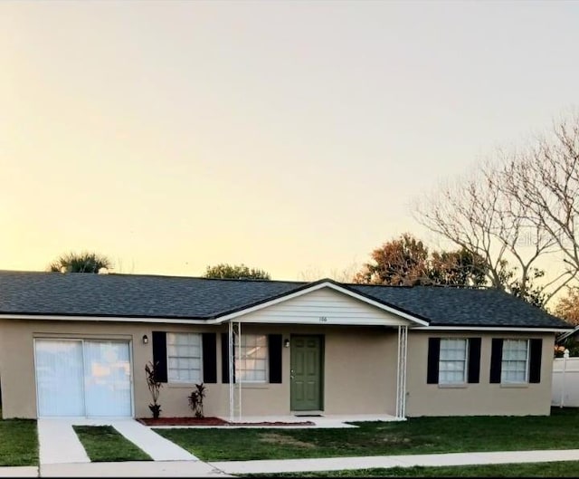 single story home with a garage and a lawn