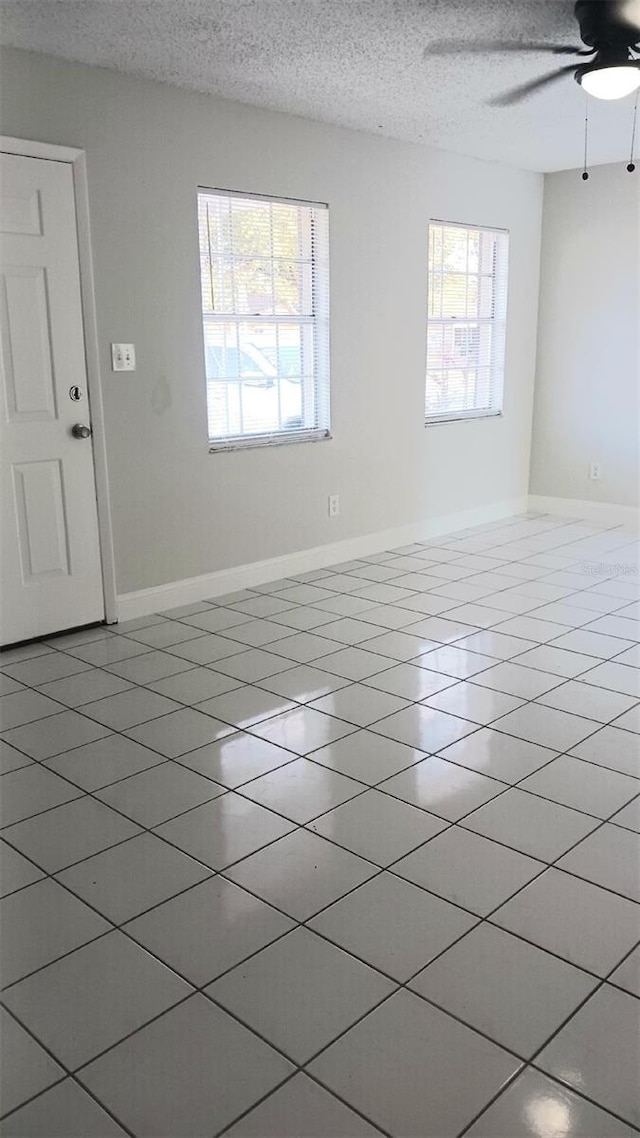 tiled spare room with ceiling fan and a textured ceiling