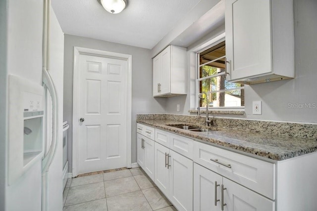 kitchen featuring white cabinets, white refrigerator with ice dispenser, sink, and light stone countertops