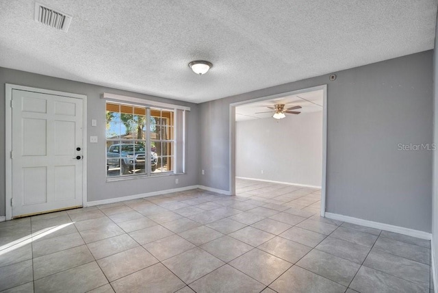 spare room featuring ceiling fan, light tile patterned floors, and a textured ceiling