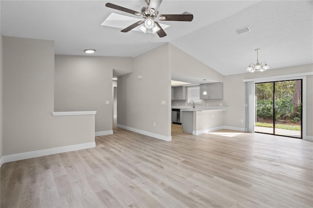 unfurnished living room with baseboards, visible vents, lofted ceiling, light wood-style floors, and ceiling fan with notable chandelier