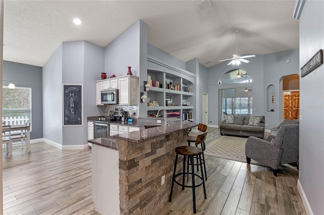 kitchen with stainless steel appliances, white cabinets, light hardwood / wood-style floors, sink, and a kitchen bar