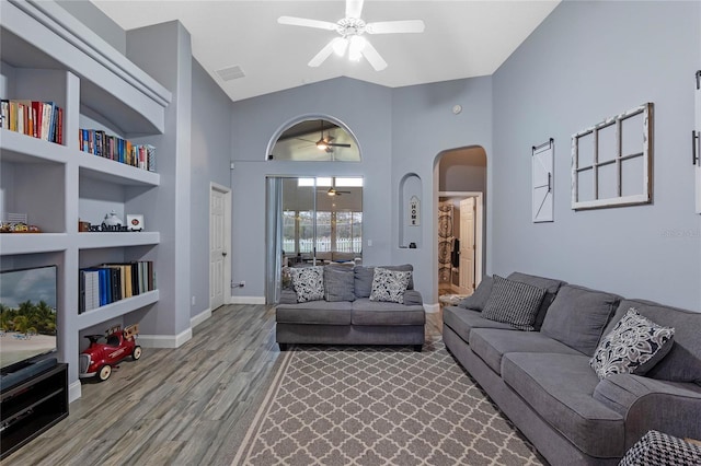 living room featuring built in features, light hardwood / wood-style floors, high vaulted ceiling, and ceiling fan