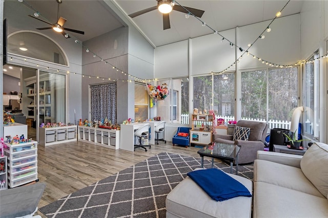 living room with ceiling fan, wood-type flooring, and a towering ceiling