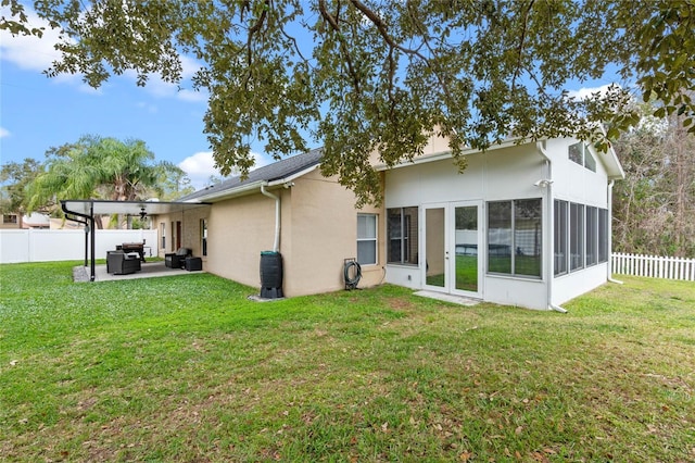 back of property with a patio, a yard, and a sunroom