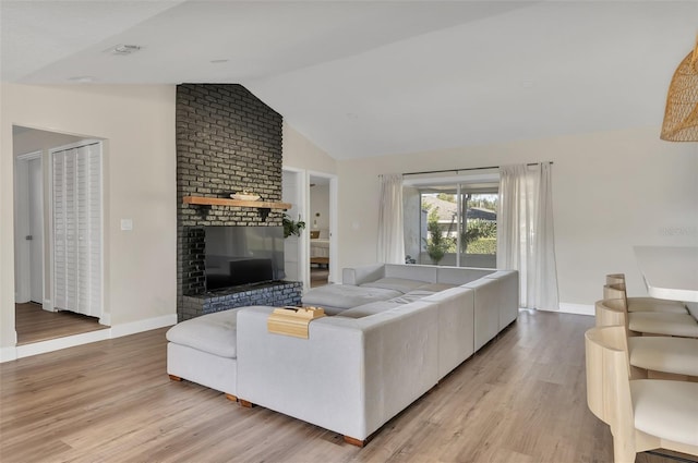 living room with a fireplace, vaulted ceiling, and light hardwood / wood-style flooring