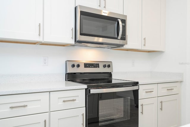 kitchen featuring light stone counters, appliances with stainless steel finishes, and white cabinets