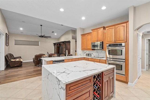 kitchen featuring appliances with stainless steel finishes, sink, a center island, light tile patterned floors, and kitchen peninsula