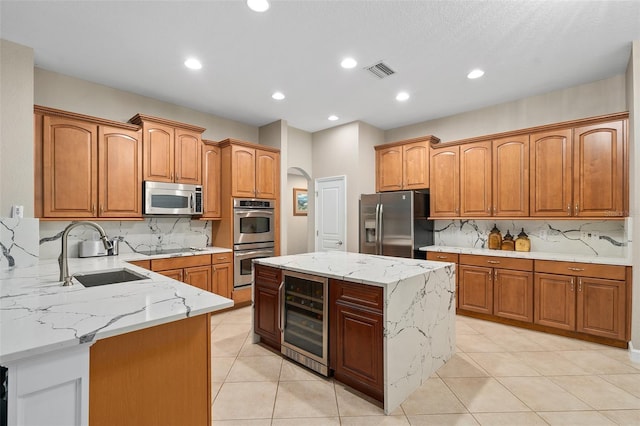 kitchen with wine cooler, light stone counters, stainless steel appliances, and a center island