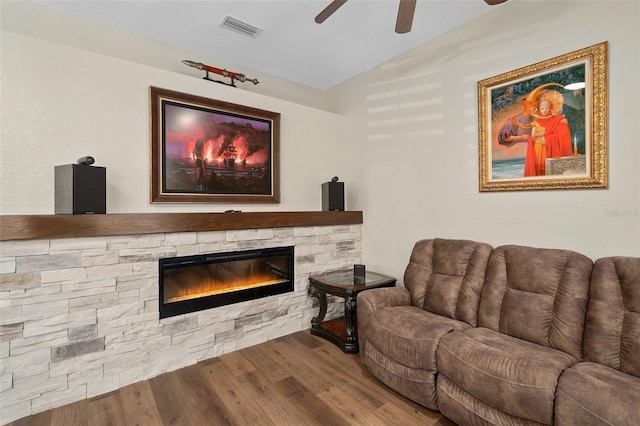 living room with a stone fireplace, hardwood / wood-style floors, lofted ceiling, and ceiling fan