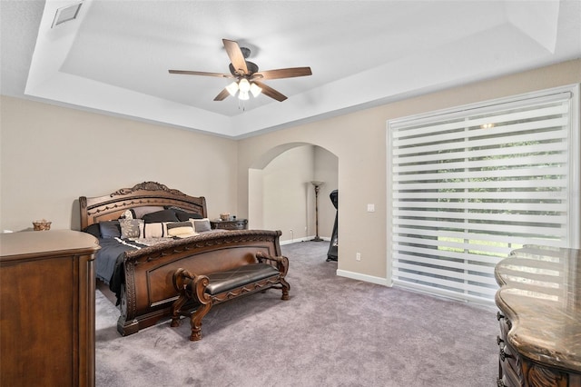 bedroom with light carpet, a tray ceiling, and ceiling fan