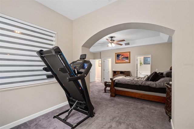 carpeted bedroom with ceiling fan, connected bathroom, and a tray ceiling