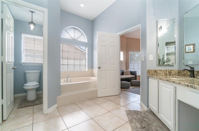bathroom with toilet, vanity, tile patterned flooring, and a relaxing tiled tub