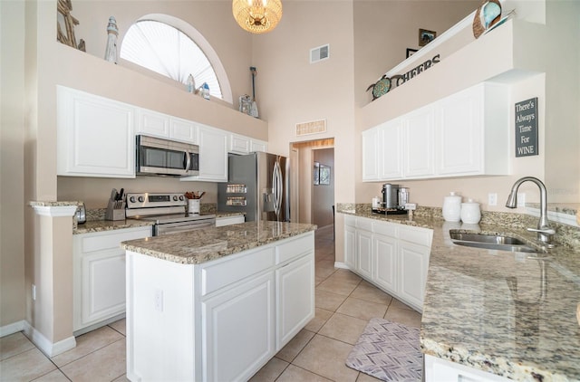 kitchen with sink, stainless steel appliances, white cabinetry, and light stone countertops