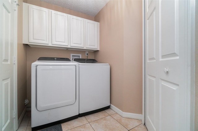 laundry room with cabinets, light tile patterned floors, a textured ceiling, and independent washer and dryer