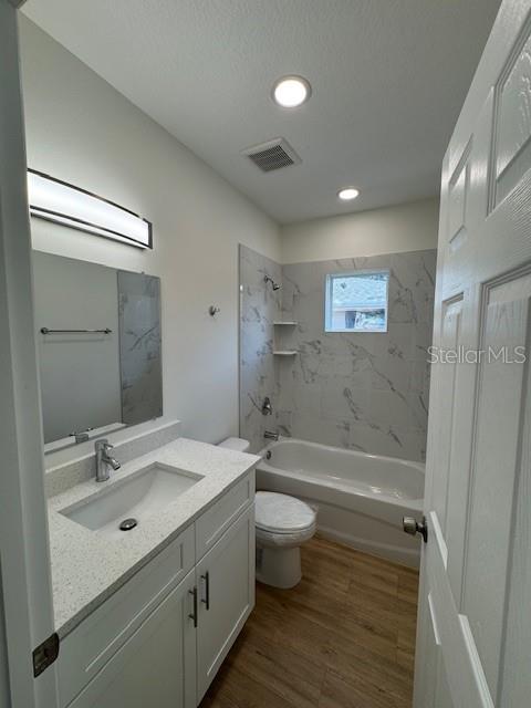 full bathroom featuring tiled shower / bath combo, wood-type flooring, vanity, and toilet