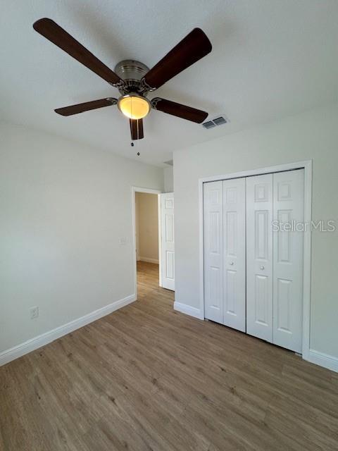 unfurnished bedroom with hardwood / wood-style floors, ceiling fan, and a closet