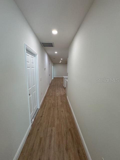 corridor with hardwood / wood-style flooring