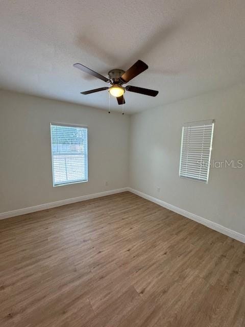 empty room featuring wood-type flooring, ceiling fan, and a textured ceiling