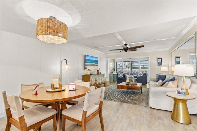 dining space with crown molding, a decorative wall, light wood-style floors, and ceiling fan