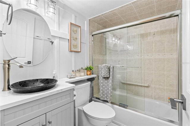 bathroom featuring bath / shower combo with glass door, vanity, and toilet